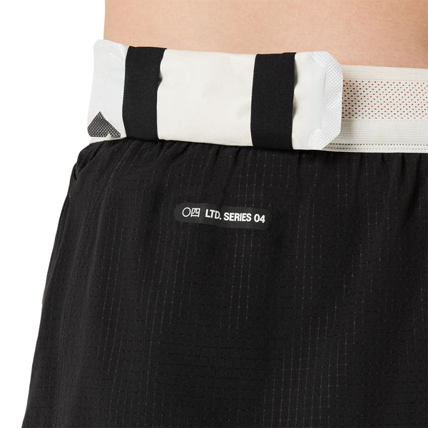 Nærbillede af en person iført Asics Limited Series Metarun Split Short, Dame, Performance Black, med hvid og sort linning og LTD. SERIES 04-mærket med minimalistiske ikoner fra ASICS Limited Series-kollektionen.