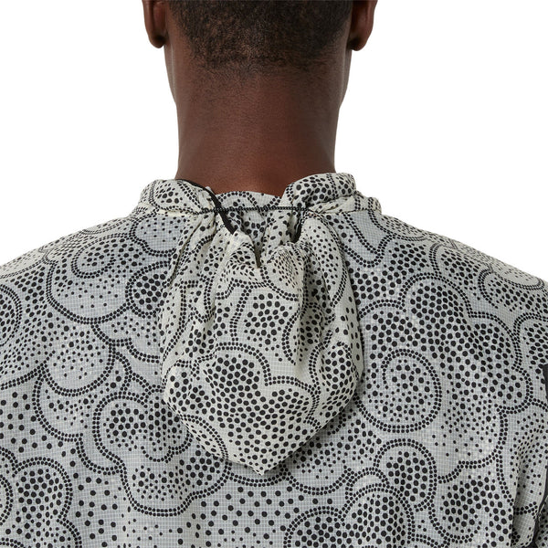 Et nærbillede af en persons øvre ryg og nakke iført ASICS Limited Series Wind Breaker Jacket, Herre, i Performance Black/Cream med et abstrakt prikket mønster og et stofbånd i halsudskæringen.