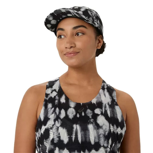 En kvinde iført ASICS’ Limited Series Metarun Tank i farvekombinationen Cream/Performance Black, udstyret med ACTIBREEZE-teknologi, samt en matchende kasket, kigger let til siden og smiler foran en ensfarvet hvid baggrund.