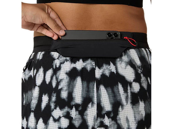 En person lægger en smartphone i den sorte lomme i linningen på ASICS’ Limited Series Metarun Split Shorts, Dame, Cream/Performance Black. Kun overkroppen og shortsene er synlige, hvilket fremhæver det praktiske design og den avancerede ACTIBREEZE-teknologi, der sikrer optimal komfort – perfekt til alle løbeshorts til kvinder, der søger både stil og ydeevne.
