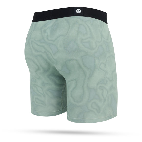 Stance Solid Green Wholester herre boxershorts har en lysegrøn farve, bølget mønster, sort linning og et centreret cirkulært logo på bagsiden. Vises mod en hvid baggrund.