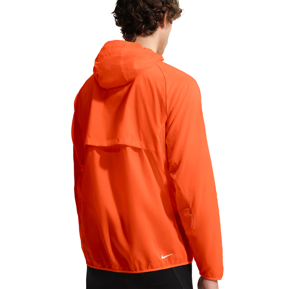 En person med kort, krøllet hår er iført en Nike ACG Trail Aireez Jkt i Safety Orange/Summit White. Letvægtsjakken med hætte har et logo nederst på ryggen og ses bagfra mod en hvid baggrund.