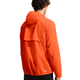 En person med kort, krøllet hår er iført en Nike ACG Trail Aireez Jkt i Safety Orange/Summit White. Letvægtsjakken med hætte har et logo nederst på ryggen og ses bagfra mod en hvid baggrund.