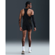 En mand i Nike M Nk Dfadv Aeroswift Jakob Singlet til mænd (Black/Metallic Gold), sorte shorts, hvide sokker og løbesko står med ansigtet vendt væk. Han har flettet hår, solbriller, et sort armlæn, og baggrunden er almindelig mørk.