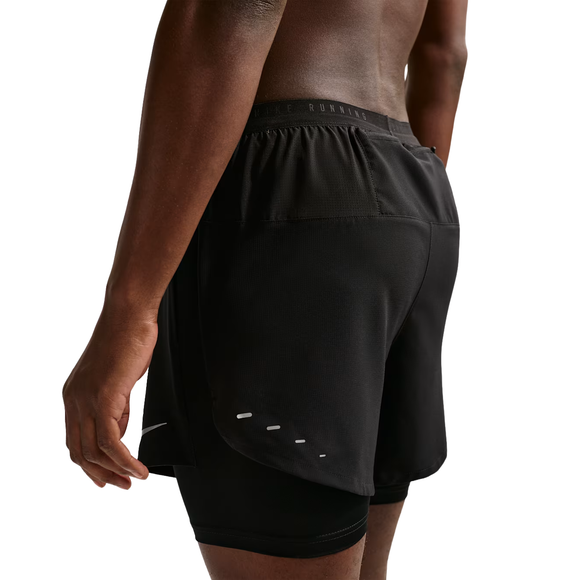 En mand er iført Nike Stride 5" Hybrid Running Shorts (Herre) i Black/Reflective Silver, der har et tætsiddende inderlag og et ventileret yderlag, set bagfra og fra siden på en hvid baggrund - perfekt til et svedtransporterende løb.