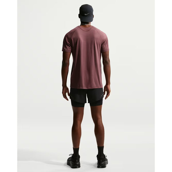 En person, set bagfra mod en hvid baggrund, er iført Nike Stride 5" Hybrid Running Shorts (Herre, Black/Reflective Silv), sammen med en rødbrun tee, sorte sokker og sko og en sort Nike-kasket - ideelt til en løbetur.