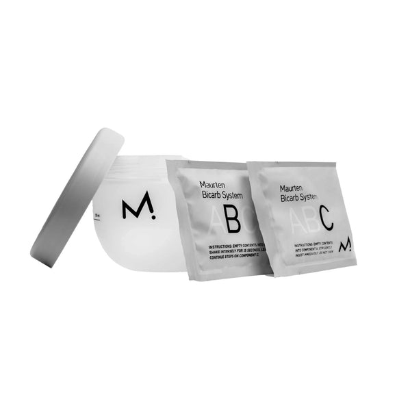 En plastikbeholder med et låg mærket »M.« og to pakker mærket »Maurten Bicarb System« vises på en ensfarvet hvid baggrund, hvor Maurten’s Bicarb System præsenteres — et innovativt natriumbikarbonat-tilskud, der er udviklet til at understøtte træning med høj intensitet.