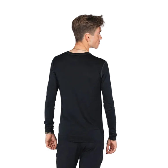 En person med kort brunt hår står med ryggen til kameraet iført Fusion Merino 150 LS Herre langærmet skjorte i sort og sorte bukser mod en almindelig hvid baggrund.