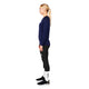 En blond kvinde med hestehale står i profil mod en grå baggrund iført Saysky W Merino Base 165 Long Sleeve, Dame, Blue shirt, sorte leggings, hvide sokker og sorte sportssko.