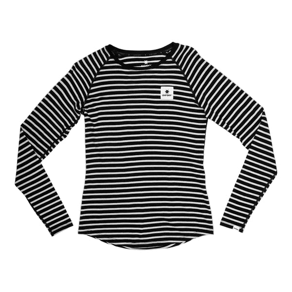 Saysky W Merino Base 165 Long Sleeve, Dame, Stripes har sorte og hvide striber, en rund halsudskæring og et lille hvidt rektangulært logopatch på venstre bryst. Trøjen er vist liggende på en lysegrå baggrund.