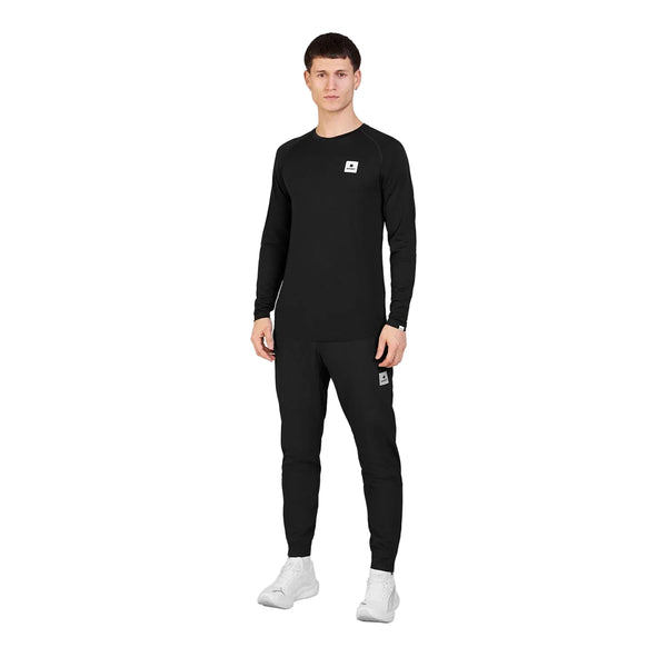 En mand iført en sort Saysky Merino Base 165 Long Sleeve, Herre, sort langærmet undertøj og sorte træningsbukser, kombineret med hvide sneakers.