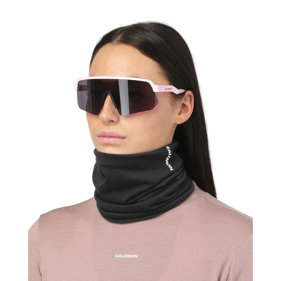 En person, der bærer en sort Salomon Merino Neck Gaiter (unisex, Deep Black) og lyse sportsolbriller til udendørsaktiviteter.