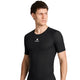 En person med kort brunt hår har en tætsiddende sort Saysky Mesh Base Layer-T-shirt på med et lille hvidt logo og en stjerne på brystet. Personen står foran en ensfarvet hvid baggrund og kigger mod venstre.