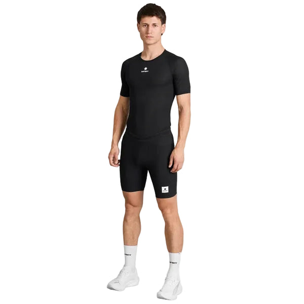En mand står med ansigtet vendt fremad iført en tætsiddende sort Saysky Mesh Base Layer-T-shirt og sorte shorts med hvide mærkelogoer, hvide strømper og hvide sportssko, foran en ensfarvet hvid baggrund.