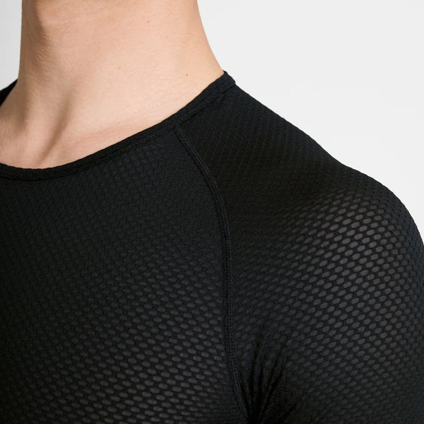 Et nærbillede af en person, der bærer Saysky Mesh Base Layer-T-shirten i sort, med et struktureret bikagemønster og et åndbart mesh-design. Kun halsen, skuldrene og den øverste del af brystet er synlige på en ensfarvet lys baggrund.