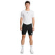 En person står med ansigtet vendt fremad foran en ensfarvet hvid baggrund og har en hvid Saysky Mesh Base Layer T-shirt på, kombineret med sorte cykelshorts, hvide sokker og hvide sportssko.