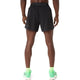 En person står med ryggen til kameraet og har ASICS Metarun 5In Shorts, Herre, Performance Black på – stilfulde løbeshorts til mænd – kombineret med lysegrønne sokker og lysegrønne løbesko. Baggrunden er helt hvid.