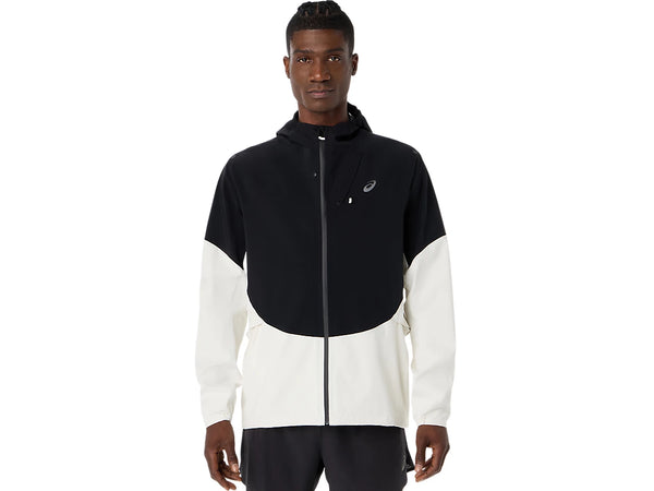 En mand står med ansigtet fremad og har ASICS Metarun Legend Jacket til mænd på – en stilfuld løbejakke til mænd i farven Cream/Performance Black. Denne vandtætte løbejakke med hætte og lynlås har ASICS-logoet på venstre bryst, hvor de cremefarvede nuancer suppleres af sorte detaljer langs ærmerne og nederst på jakken.