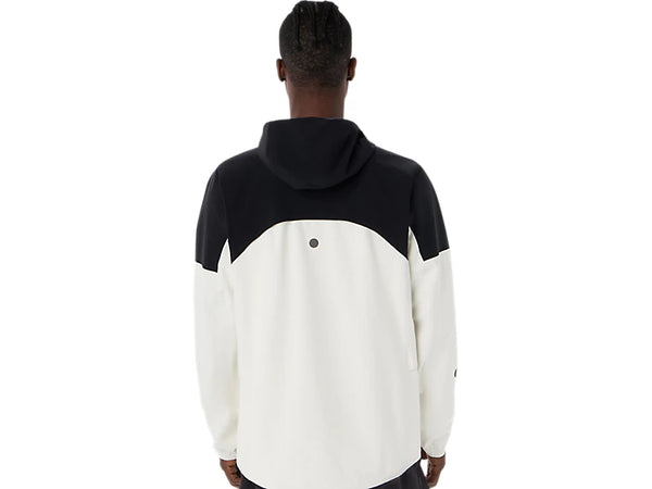 Der ses en person set bagfra iført Asics Metarun Legend Jacket, Herre, i farvekombinationen Cream/Performance Black. Jakken er designet som en vandtæt løbejakke og har en sort overdel og ærmer, mens resten er cremefarvet. Hætten er trukket op, og på en ensfarvet hvid baggrund fremstår denne stilfulde løbejakke til mænd perfekt.