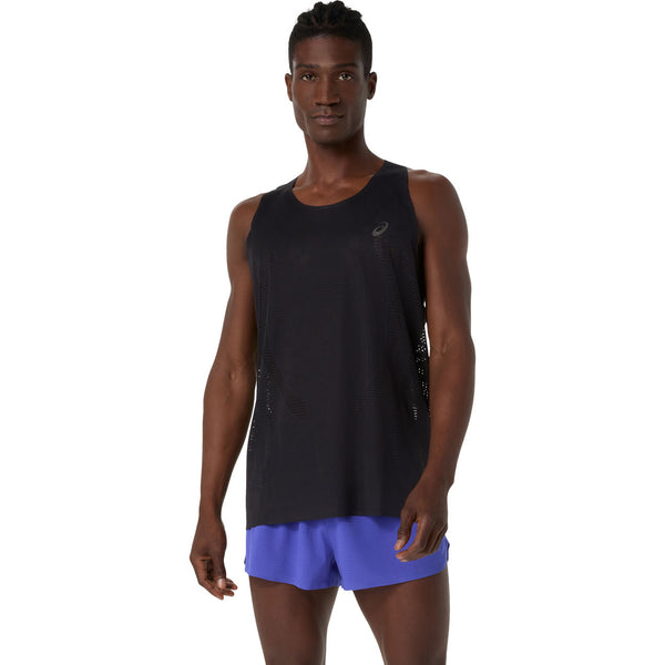En mand står med ansigtet fremad i en Asics Metarun Singlet, Herre, Performance Black og blå løbeshorts (løbetøj herre) mod en almindelig hvid baggrund.