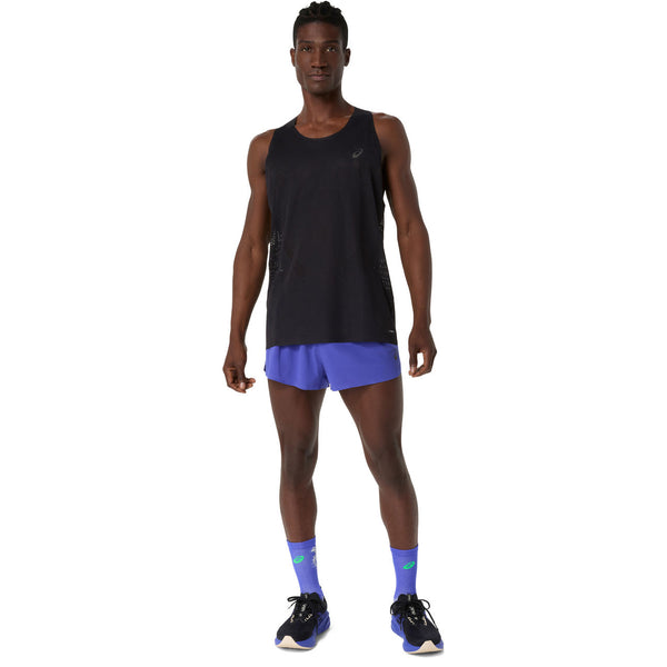 En mand kigger fremad i en sort Asics Metarun Singlet (Herre, Performance Black), blå løbeshorts, blå strømper med grønne logoer og mørkeblå løbesko - og fremhæver stilfulde løbetøj herre.