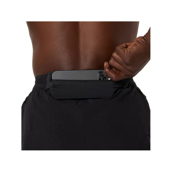 En person stikker en smartphone ned i baglommen med lynlås på sine Asics Metarun Split Short, Herre i Performance Black, og holder linningen åben for at fremhæve disse løbeshorts i aktion.