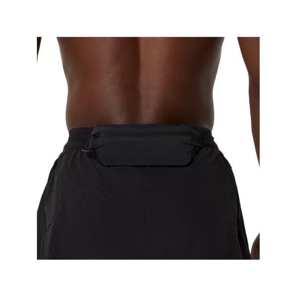 Et nærbillede af en persons lænd og talje iført Asics Metarun Split Short, Herre, Performance Black, med en lille sort lynlåslomme i linningen - ideelle performance løbeshorts til enhver træning.