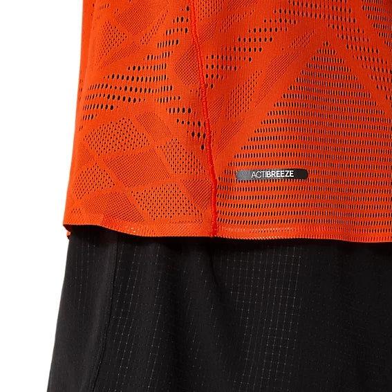 Nærbillede af en orange sportstrøje i netstof, Asics Metarun SS Top, Herre i farven Cherry Tomato, med geometriske ventilationshuller, båret over sorte shorts med et diskret gittermønster.