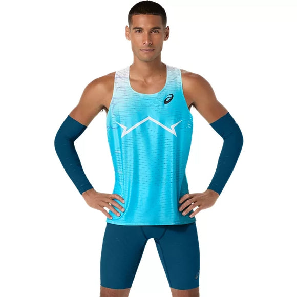 En mand står med ansigtet vendt fremad og hænderne på hofterne. Han er iført en Asics Metaspeed Singlet, Herre, Aquarium, matchende blå kompressionsshorts og blå armvarmere. Baggrunden er ensfarvet hvid.