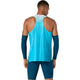 Der ses et billede af en mand set bagfra, iført en Asics Metaspeed Singlet, Herre, i farven »Aquarium«, blå kompressionsarmvarmere og blå sportsshorts på en ensfarvet hvid baggrund.