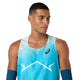 En mand med kort, mørkt hår har Asics Metaspeed Singlet, Herre i farven »Aquarium« på – en blå løbesinglet med et hvidt zigzagmønster og Asics-logoet – mens han står foran en ensfarvet hvid baggrund og kigger let mod venstre.