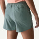 En person ses fra taljen og ned iført Patagonia Multi Trails Shorts 5½in til kvinder i Blue Sage, med elastisk linning og en baglomme.