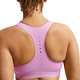 En kvinde med flettet hår ses bagfra iført Nike Nk Swift Hs Bra i Lt Magenta/Reflective Silver med Dri-FIT-teknologi, ventilationshuller og refleksdetaljer - ideelt til højintensiv træning.