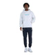 En person har en lysegrå New Balance NYC Marathon Athletics Graphic-hoodie (herre, farven Ash Heather) med et blåt motiv på brystet, mørke joggingbukser og lyse sportssko på.