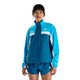 En person iført en blå og turkis New Balance NYC Marathon-jakke, Dame, Streamsong-træningsjakke med lynlås og matchende sportsshorts.
