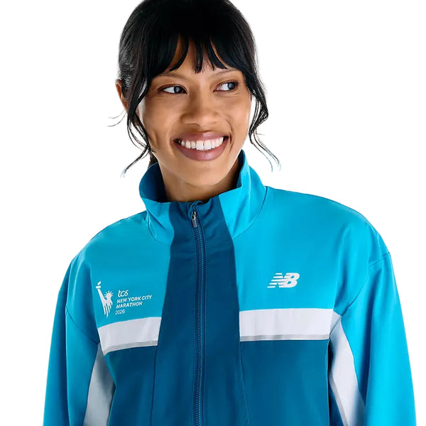 En person iført en lyseblå, vind- og vandafvisende New Balance NYC Marathon-jakke, model Dame, Streamsong, med løbets logo på brystet.