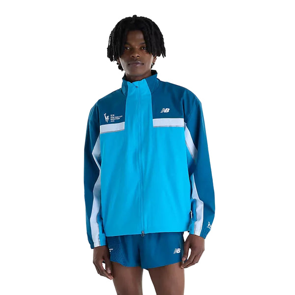 En person iført en blå New Balance NYC Marathon-jakke, Herre, Altitude med lynlås og hvide detaljer samt matchende blå sportsshorts.