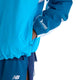 En blå New Balance NYC Marathon-jakke, Herre, Altitude, med hvide indsætninger på ærmerne og New York Road Runners-logoet på manchetten, kombineret med mørkeblå sportsshorts.