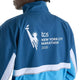 Bagside af en vind- og vandafvisende New Balance NYC Marathon-jakke, Herre, Altitude, med et hvidt motiv af Frihedsgudinden og teksten tcs NEW YORK CITY MARATHON 2026.