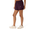 En person står i en neutral stilling iført Asics Nagino Run 2-N-1-shorts til kvinder i farven Dark Aubergine, der er forsynet med et lille Asics-logo, sammen med en matchende top og lyse sportssko på en ensfarvet hvid baggrund. Nagino Run 2-N-1-shortsene fra Asics er designet til at give komfort og stil til hver eneste løbetur.