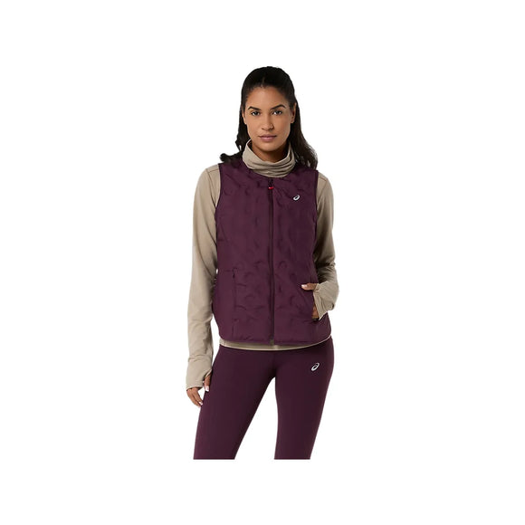 En kvinde med langt mørkt hår har en beige rullekravebluse på, en mørk auberginefarvet ASICS Nagino Run Padded Gilet til kvinder og matchende lilla leggings. Hun står med ansigtet vendt fremad og den ene hånd i vestens lomme foran en hvid baggrund.