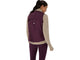 Der ses et billede bagfra af en kvinde med mørkt hår i hestehale, iført en beige langærmet bluse og ASICS Nagino Run Padded Gilet til kvinder i farven Dark Aubergine, kombineret med lilla leggings, mens hun står foran en ensfarvet hvid baggrund.