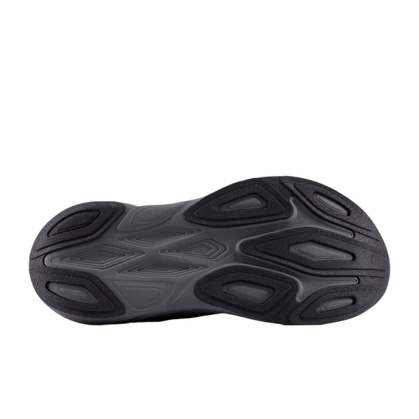 Billedet viser sålen på New Balance Freshfoam More V6 herre løbesko i sort med et struktureret mønster af ovale og buede riller, der giver maksimal komfort og greb. Skoen vises med sålen opad på en almindelig hvid baggrund.