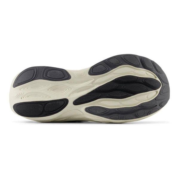 Billedet viser bunden af en New Balance Freshfoam 1080v14 Dame Black-sneaker med en bølget, tekstureret lys beige og sort gummisål med flere hævede, buede sorte trækkraftzoner til blød støddæmpning.