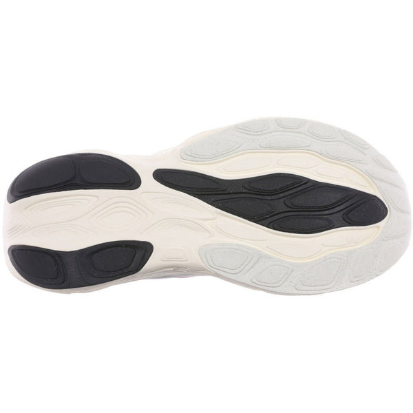 Billedet viser ydersålen på New Balance Freshfoam 1080v14 Dame White-sneakeren med en bølget slidbane. Den overvejende råhvide sål har sort gummi ved tåen, hælen og i midten for at give bedre greb og komfort.