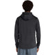 En person med kort krøllet hår ses bagfra iført en New Balance Heat Grid Balaclava Hoodie for men i sort og lysegrå shorts, stående mod en almindelig hvid baggrund.