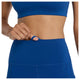 En person i New Balance Sleeck Pocket High Rise Tights, Dame, Galaxy Blue, trækker i en lille indvendig løkke i linningen for at afsløre den justerbare funktion. Nærbilledet fremhæver tightsens funktionelle design og pasform.