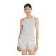 En person står med ansigtet fremad og er iført New Balance Race Day Ultra Light Singlet til kvinder i Grey Matter med et lille rødt logo og matchende shorts på en almindelig hvid baggrund.