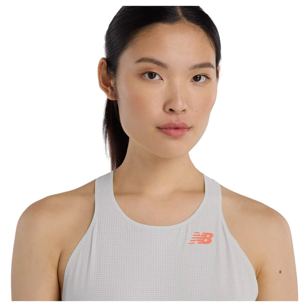 En kvinde med langt mørkt hår, der er bundet tilbage, bærer en New Balance Race Day Ultra Light Singlet, Dame, i Grey Matter, og står med front mod en almindelig hvid baggrund.