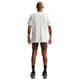 En person står med front mod kameraet iført Nike ACG Df Tee Std Trail Logo, Herre, Summit White, brune, tætsiddende shorts, sorte sokker og sorte sportssko på en hvid baggrund.